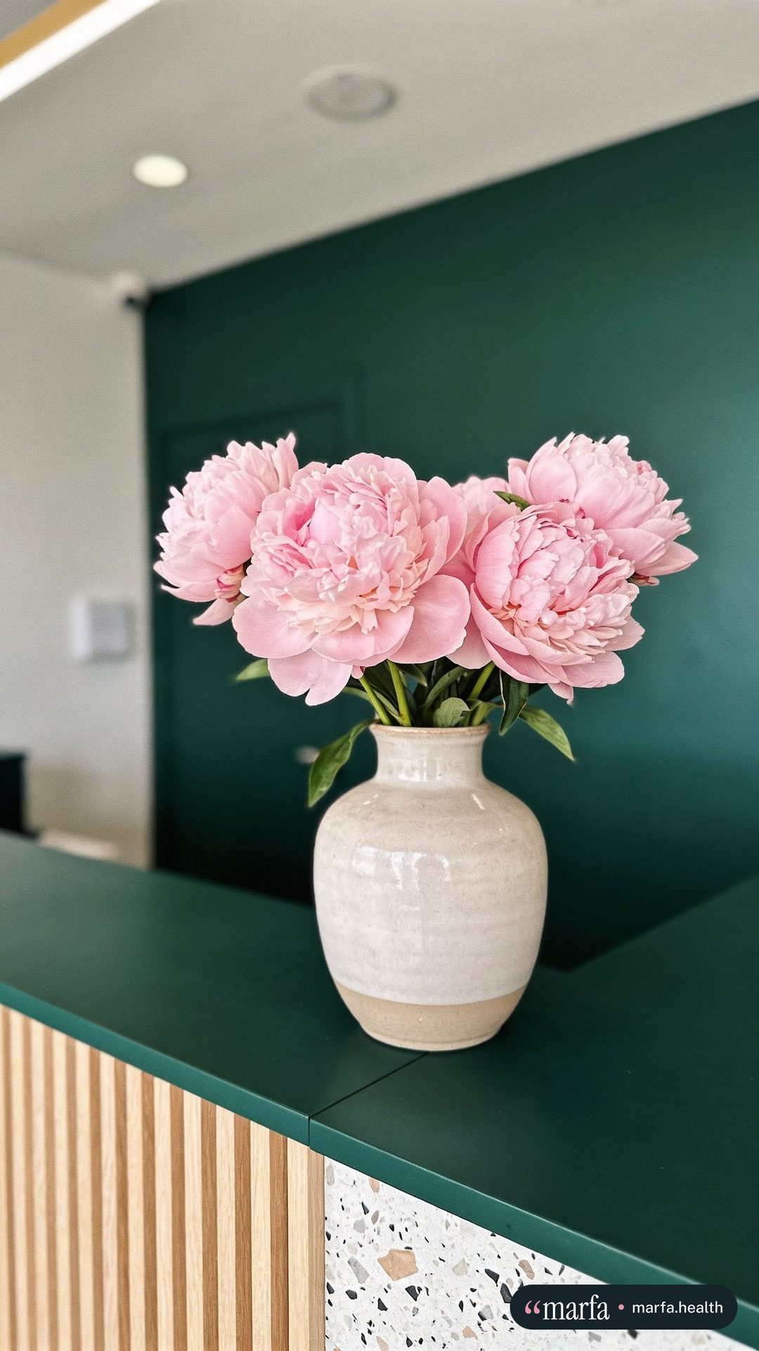 Reel cover of pink peonies in a ceramic vase on a green counter